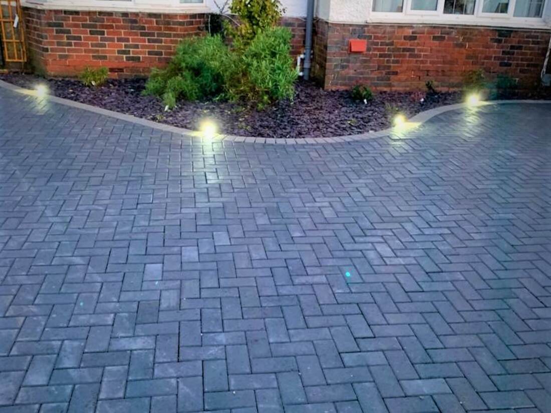 The same frontage after work, with a herringbone block paved driveway and recessed lighting