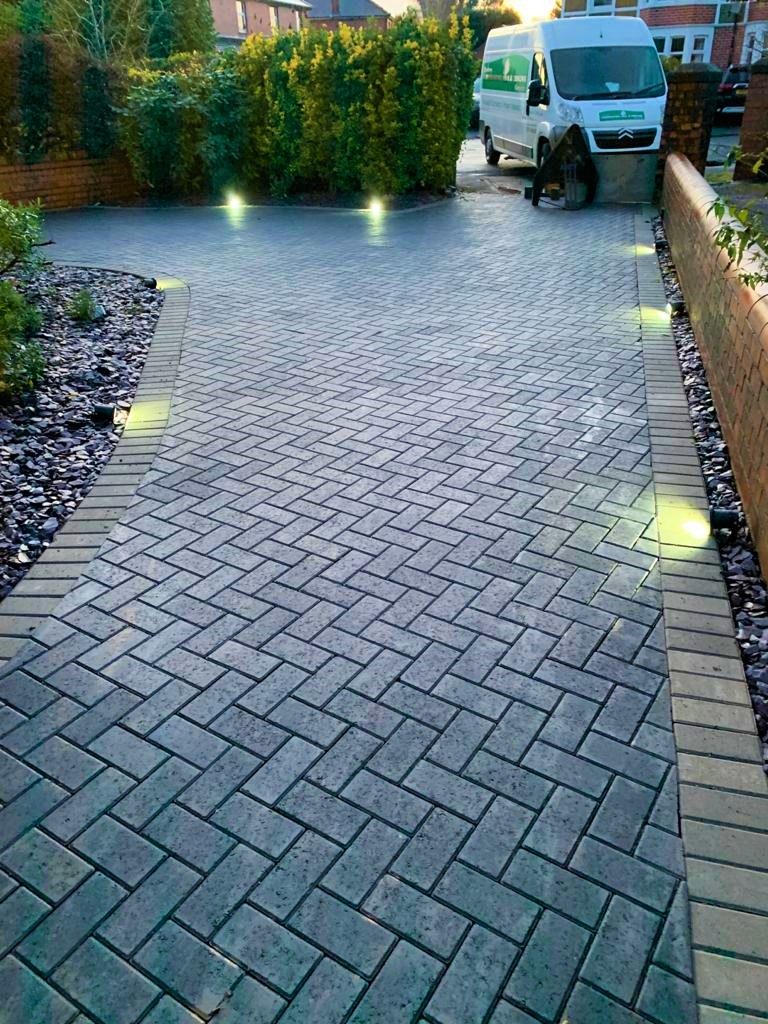 Block paved driveway illuminated by recessed lights