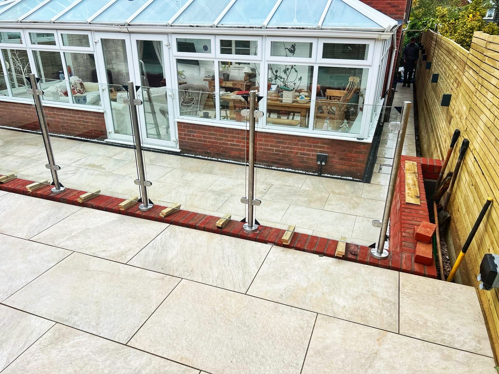 Paved patio with glass balustrade beside a conservatory