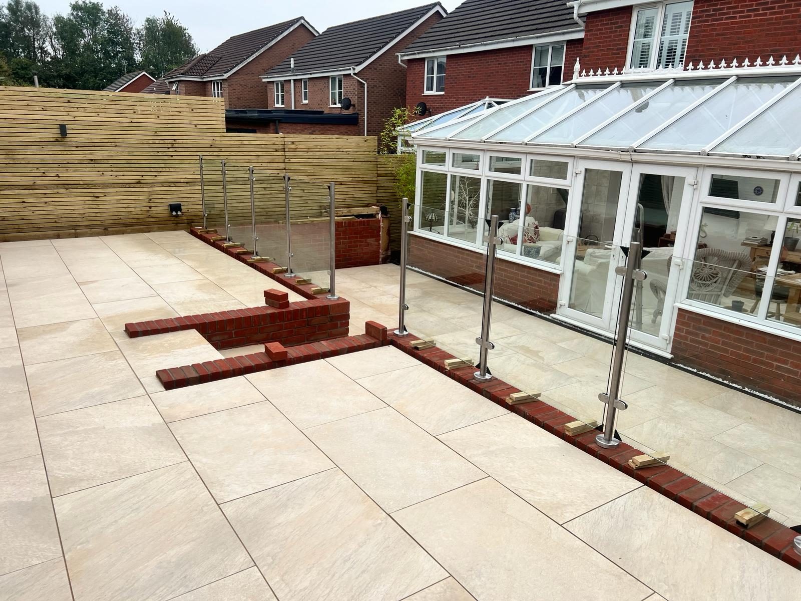 Wide view of a finished sandstone patio beside a conservatory
