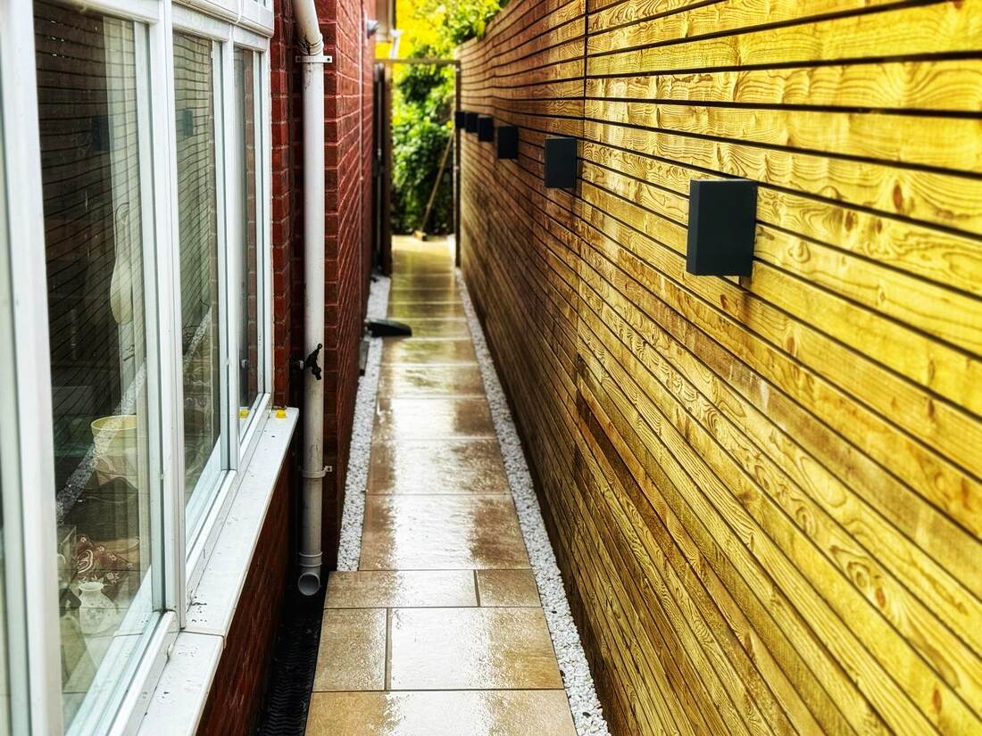 Horizontal cedar slat fencing alongside a sandstone paved side path